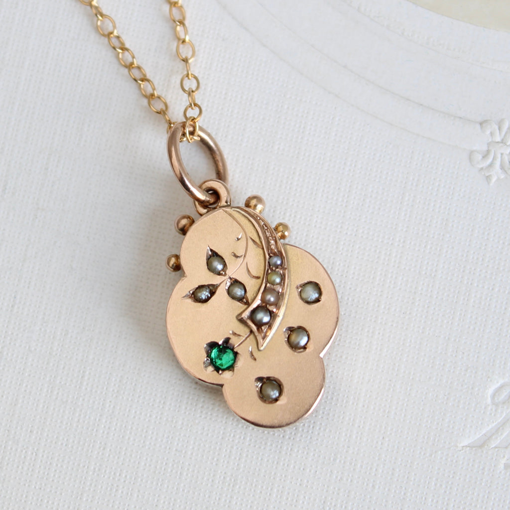 smalll sized yellow gold locket with flower engraving set with pearls and faux emerald, on a chain