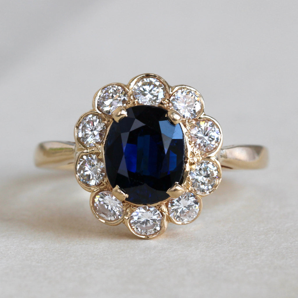 yellow gold ring with oval twilight blue natural sapphire with a halo frame of bright white diamonds