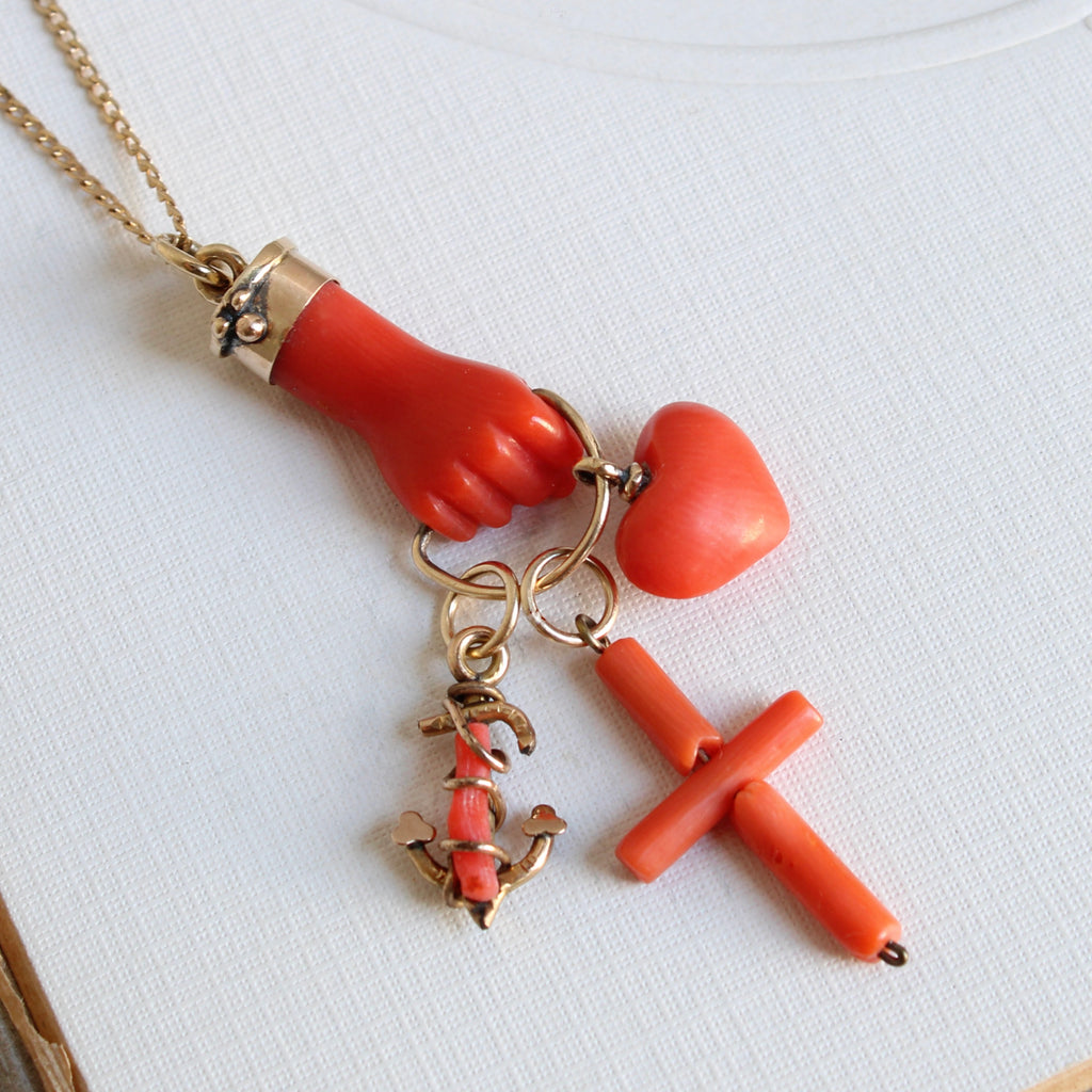 carved coral hand holding a carved coral heart, cross and anchor