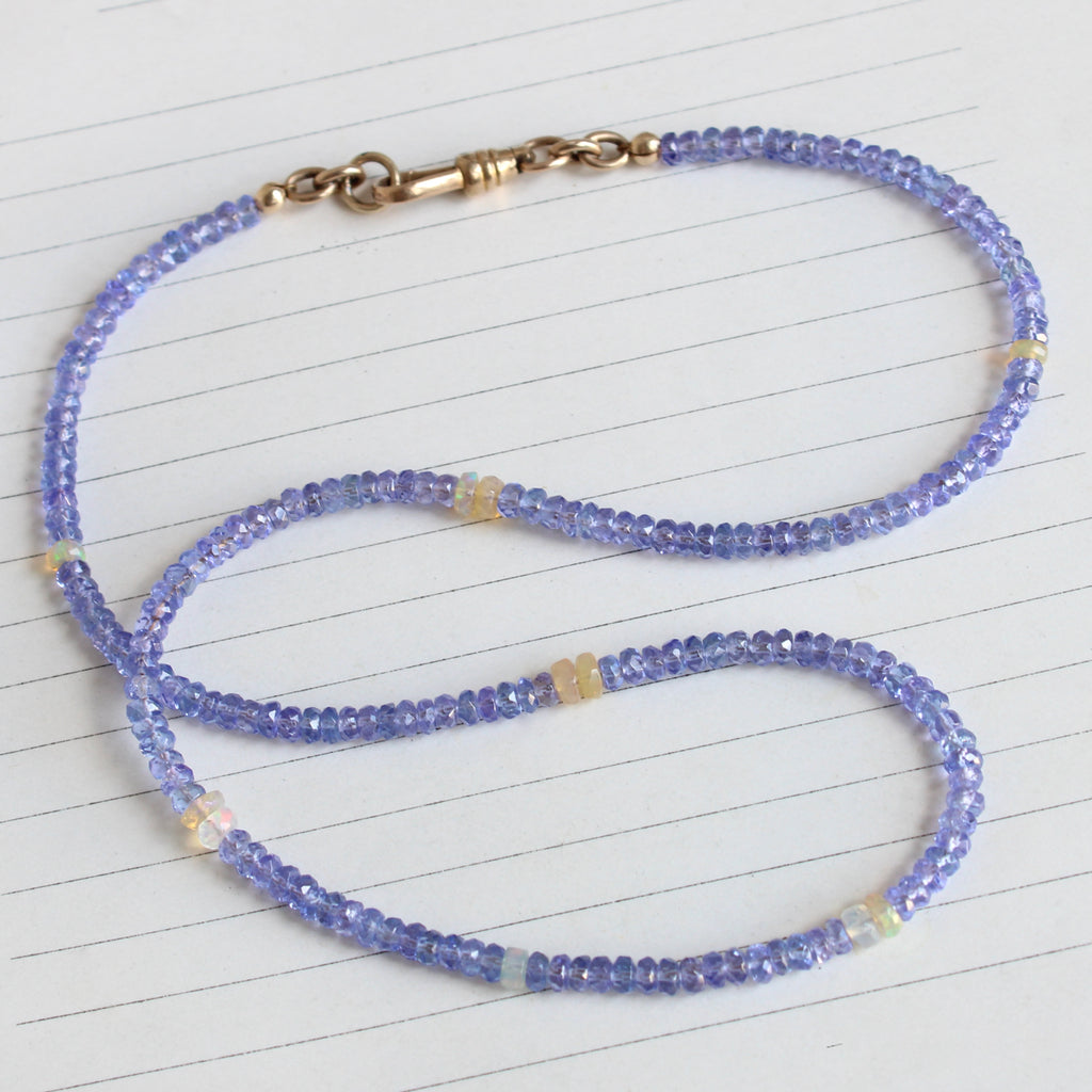 tanzanite bead necklace with opal spacers and a gold charm clip clasp