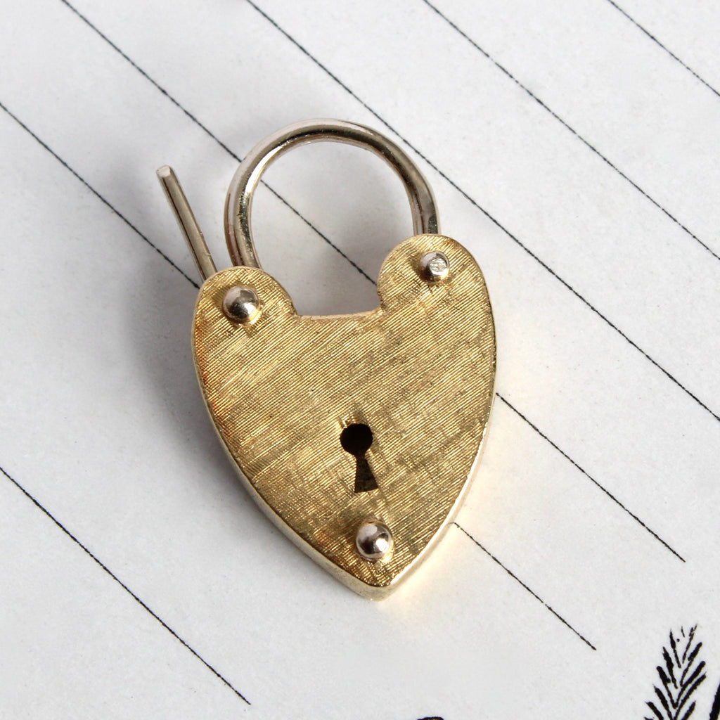 heart shaped padlock clasp that opens and shuts with a yellow gold body and white gold handle and accents