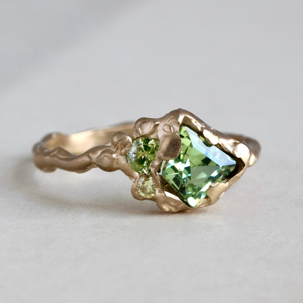 handmade branch design yellow gold ring with a kite shaped natural green sapphire and two natural green diamond 