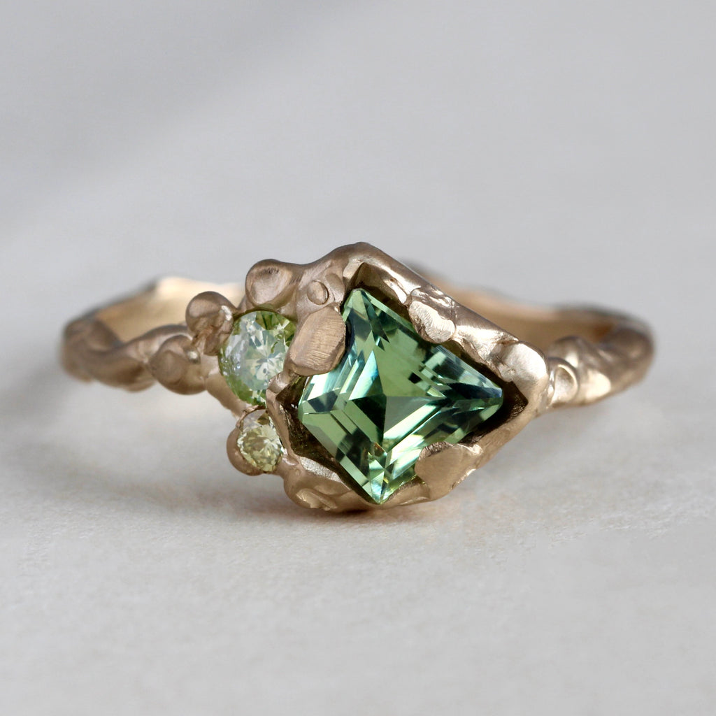 organic branch style yellow gold ring with a kite shaped natural green sapphire with two natural green diamond accents.