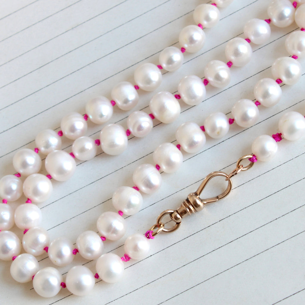 large white pearls knotted on deep pink silk with yellow gold dog clip clasp