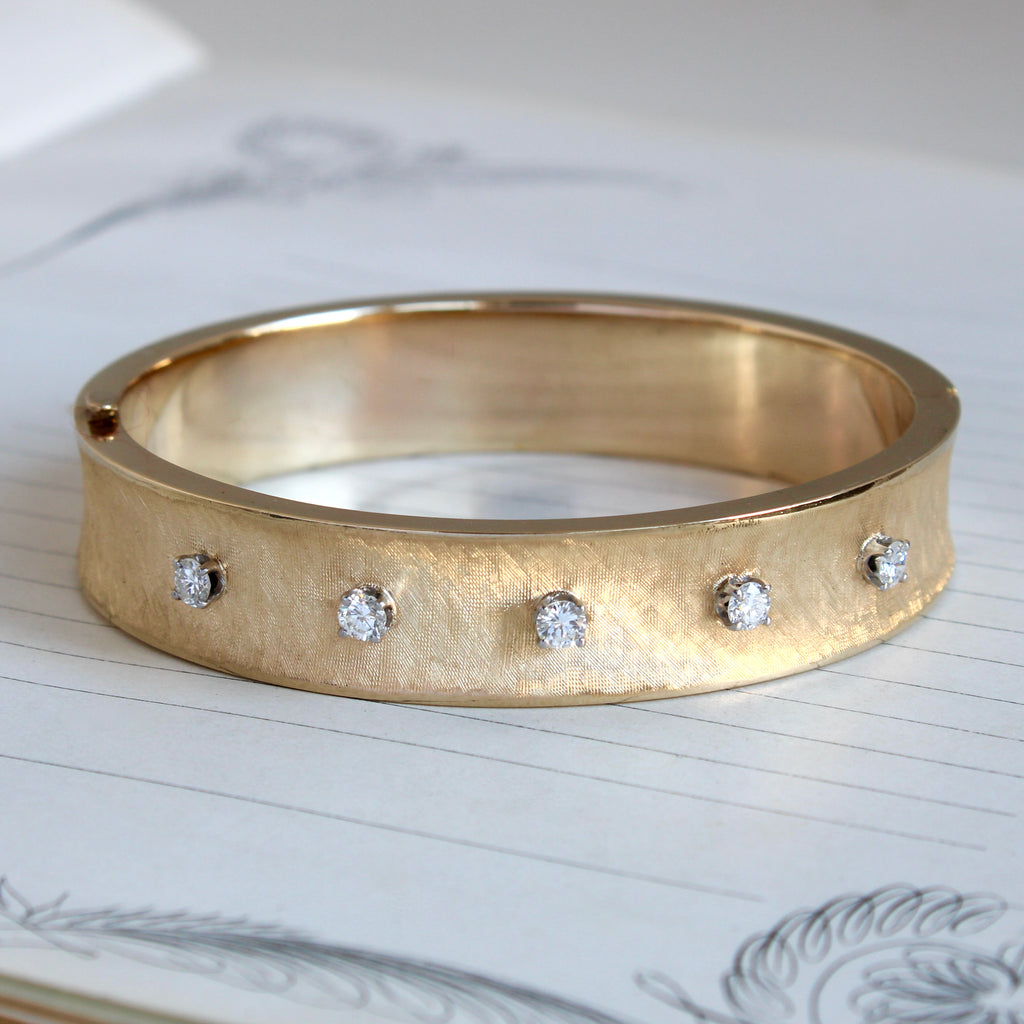 wide yellow gold bangle with a textured surface set with 6 bright diamonds across the front