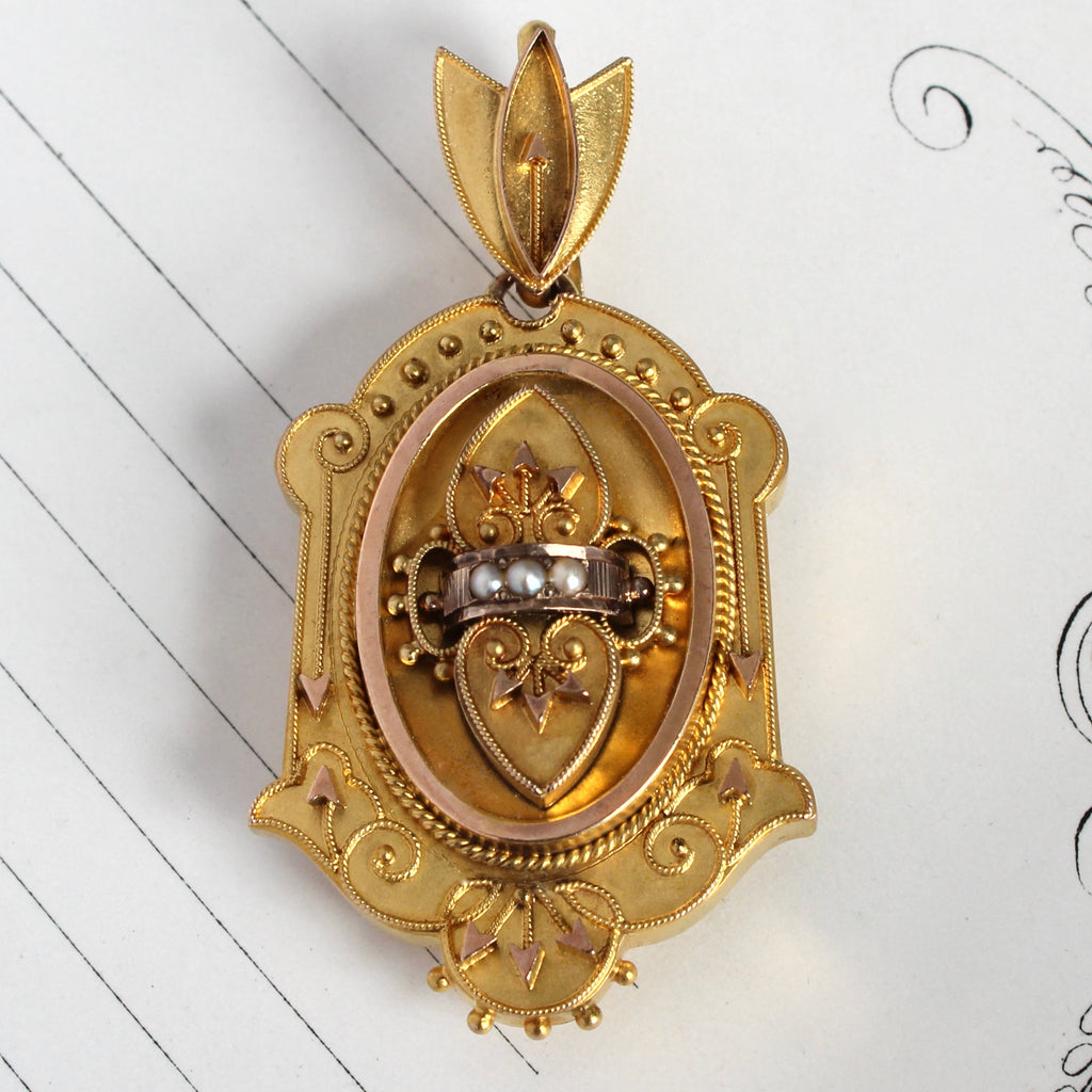 Antique yellow gold locket with filigree scroll details and little hearts studded with tiny pearls and a leaf styled bail.