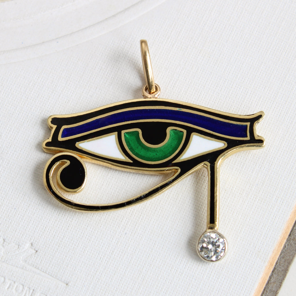 egyptian style yellow gold eye pendant colored with green blue white and black enamel and a diamond accent