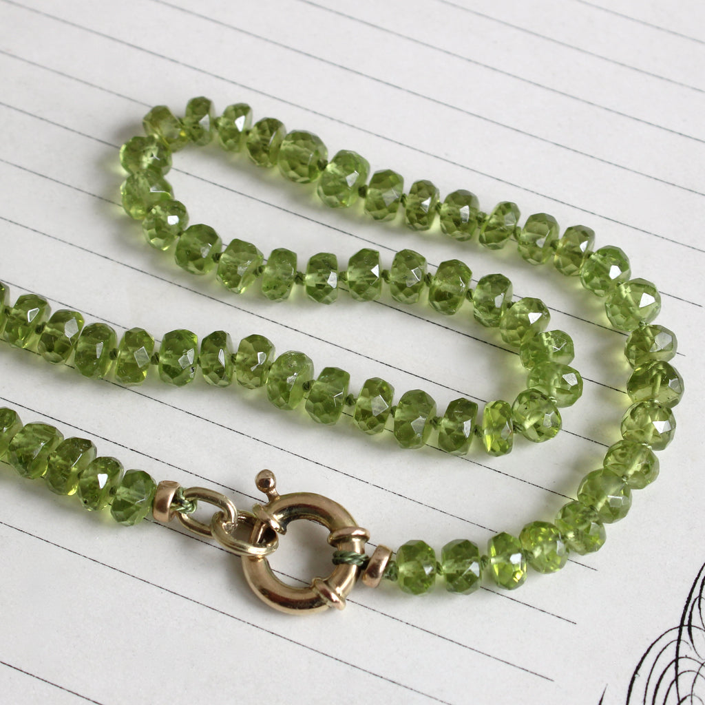 rich green peridot beads with faceted edges on green silk with a round gold clasp