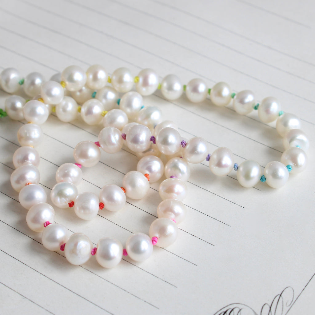 necklace of white freshwater pearls knotted on bright rainbow silk so there's a different color knot between each pearl