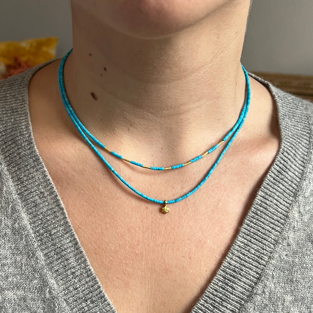 double strand necklace with bright blue turquoise beads that have high karat bead accents and a tiny gold star charm