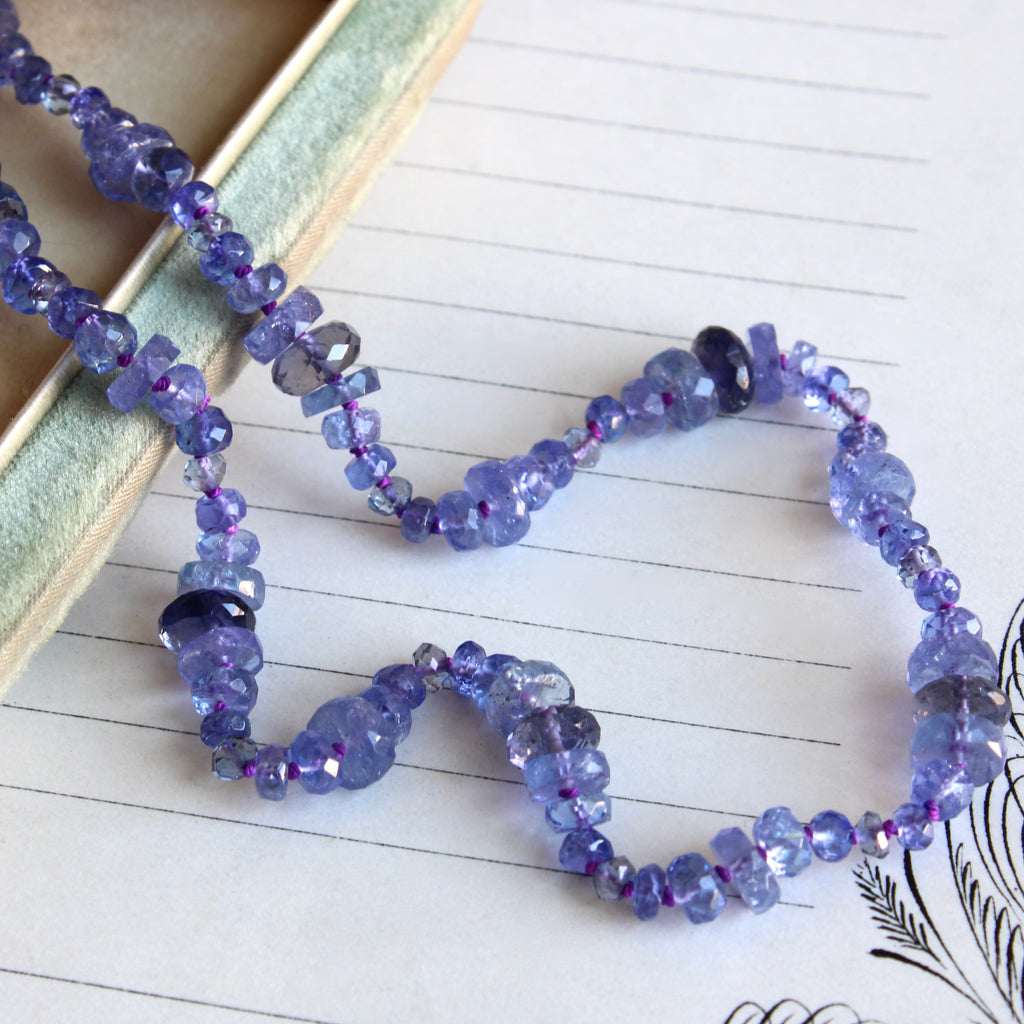 faceted blue-purple tanzanite beads of varying widths knotted so the strand has a scallopped edge.