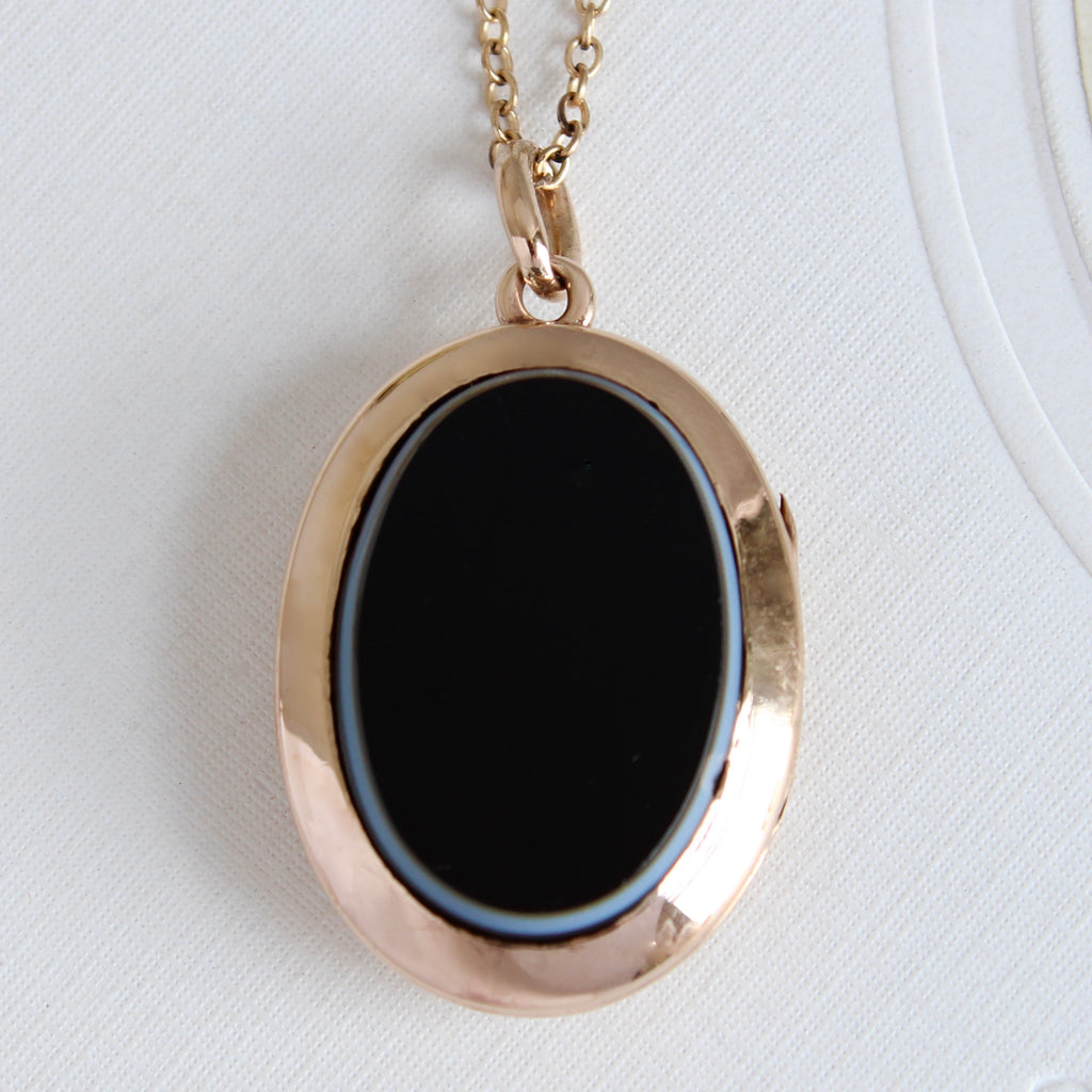 antique locket in 14k yellow gold with a black agate front cover and brown agate back cover, on a chain