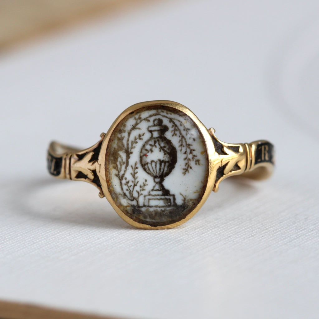 18th century mourning ring with a hand-painted sepia miniature of a funeral urn framed by weeping willow branches. The details on the black enamel band identify this as a memorial piece for R. Cook, with an obituary date of November 29th, 1774 at the age of 71.