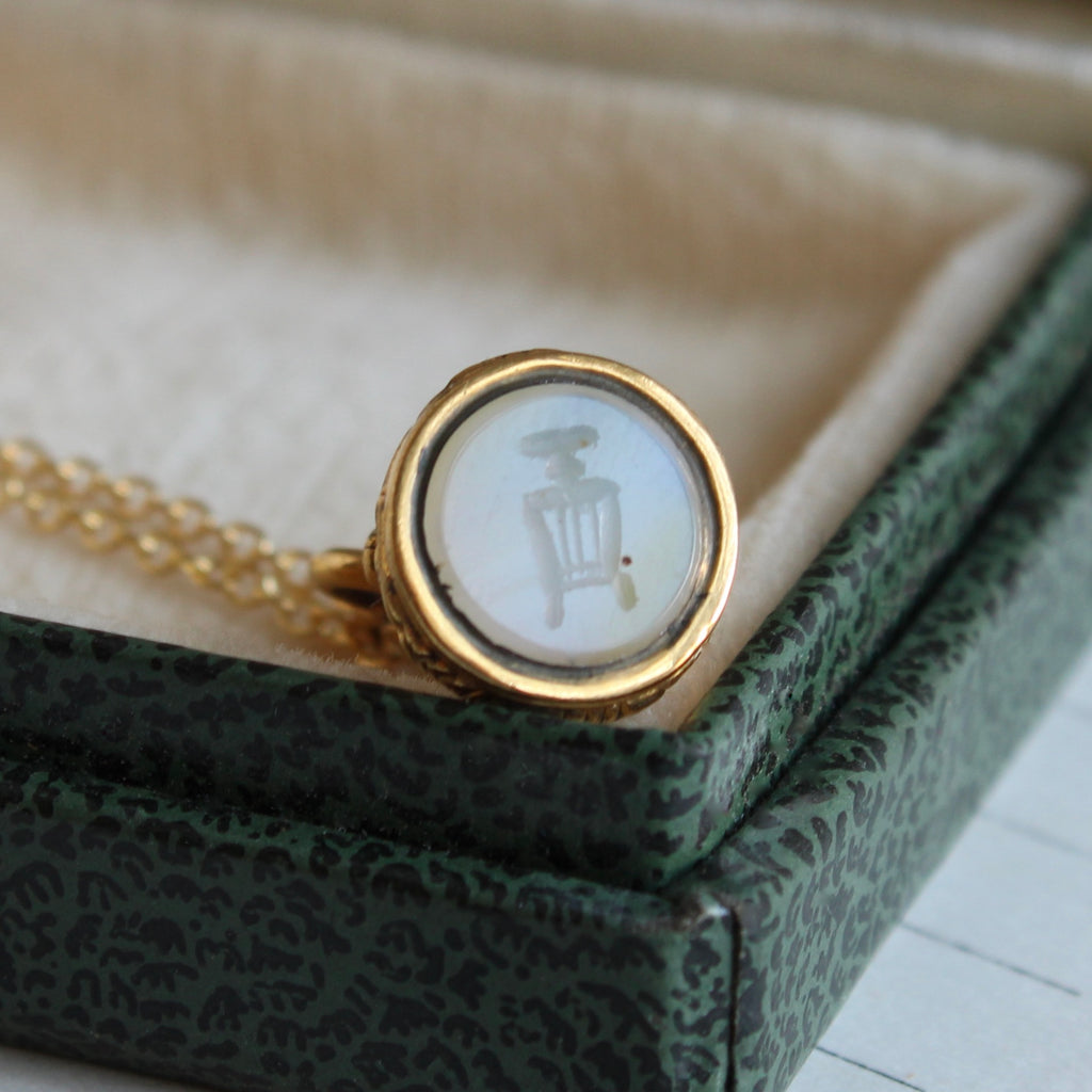 a tiny wax seal engraved with the image of an antique book press on the white agate stone set on the bottom