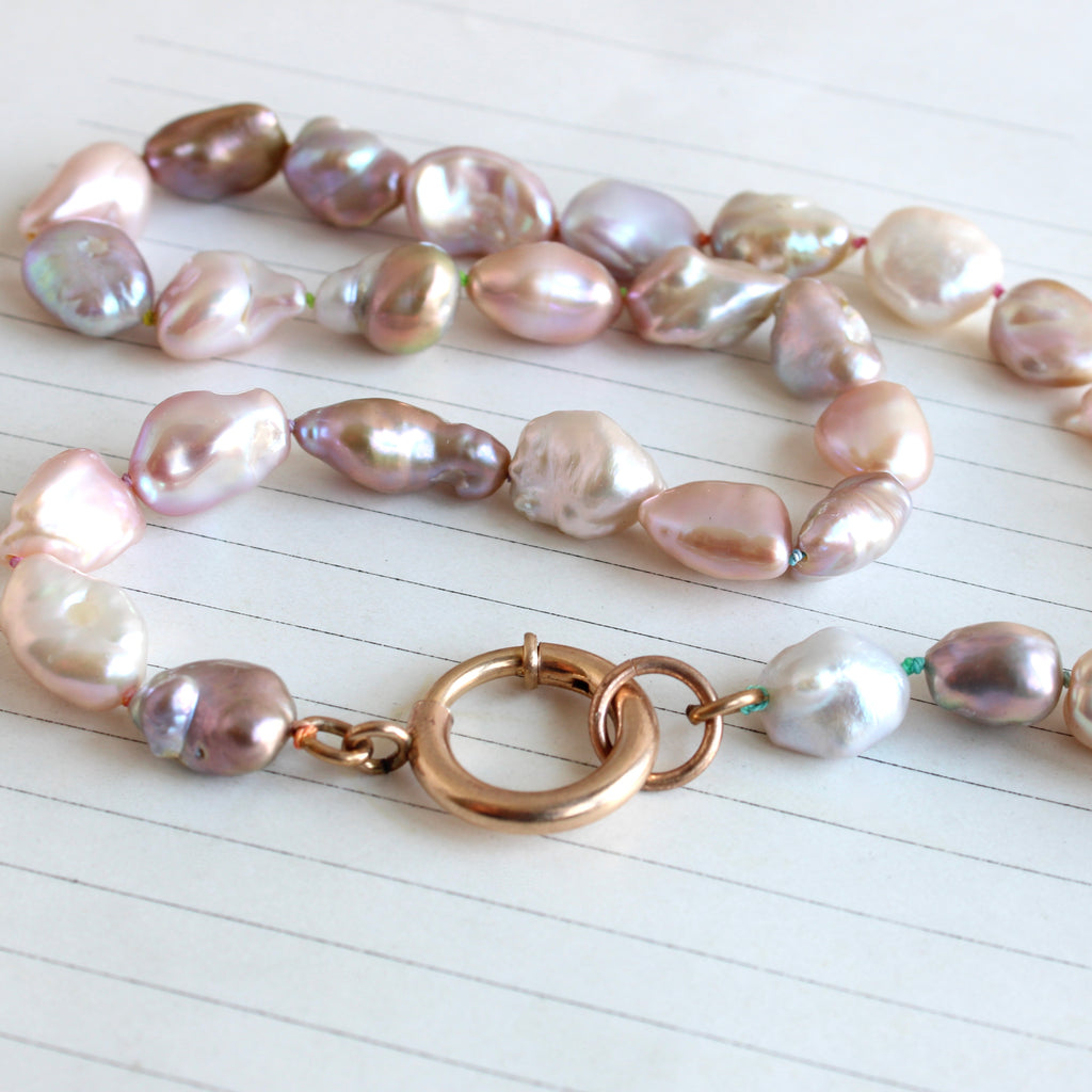 irregular shaped pearls with pinkish and purplish color knotted on rainbow silk with a large gold clasp