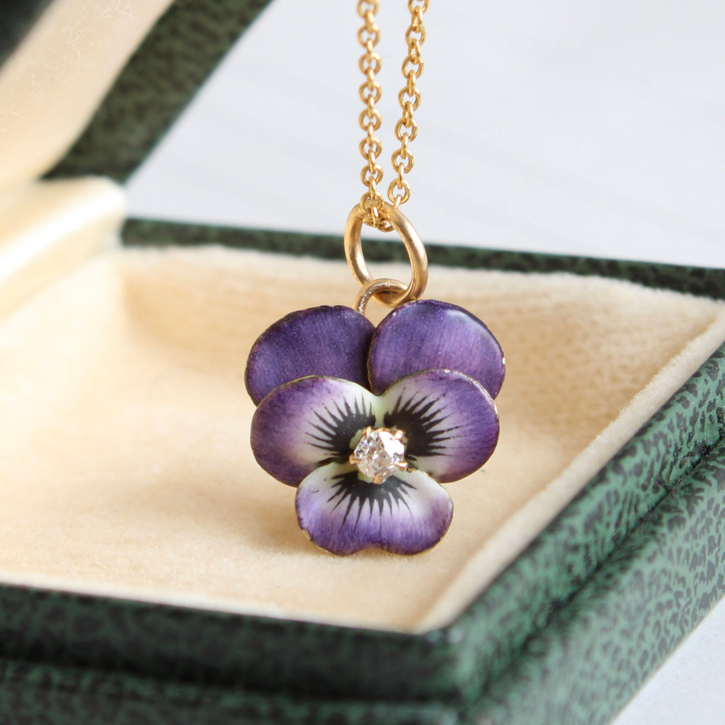 miniature gold pansy charm enameled in dark purple and white with a diamond in the center and a gold chain