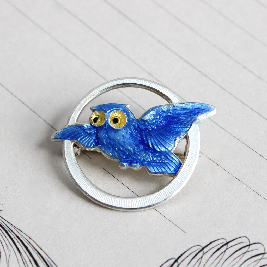 vintage silver pin with flying owl enameled in blue with yellow eyes