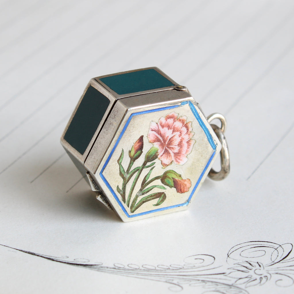 a small silver hexagonal pillbox pendant enamel ed on the top with a pink carnation