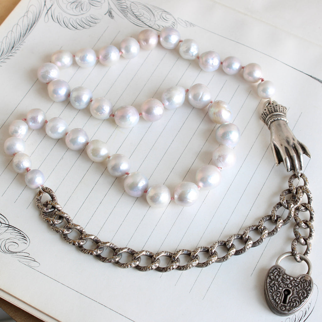 necklace with large white pearls with silver curb chain section and a silver clasp shaped like a hand