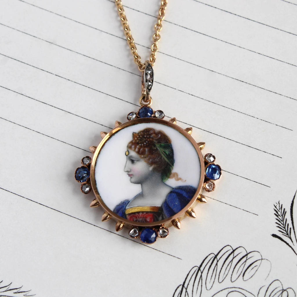 Antique yellow gold woman cameo round pendant with sapphires and diamonds at the compass points around the painting.