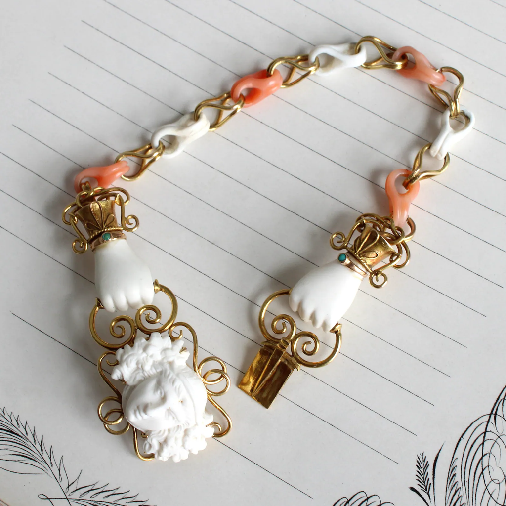 Antique yellow gold bracelet with carved white and pink coral chain links and carved white coral hands holding clasp set with cameo of bacchus also carved from white coral.