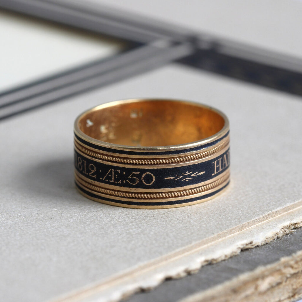 Antique yellow gold band with black enamel details and dated 1812.