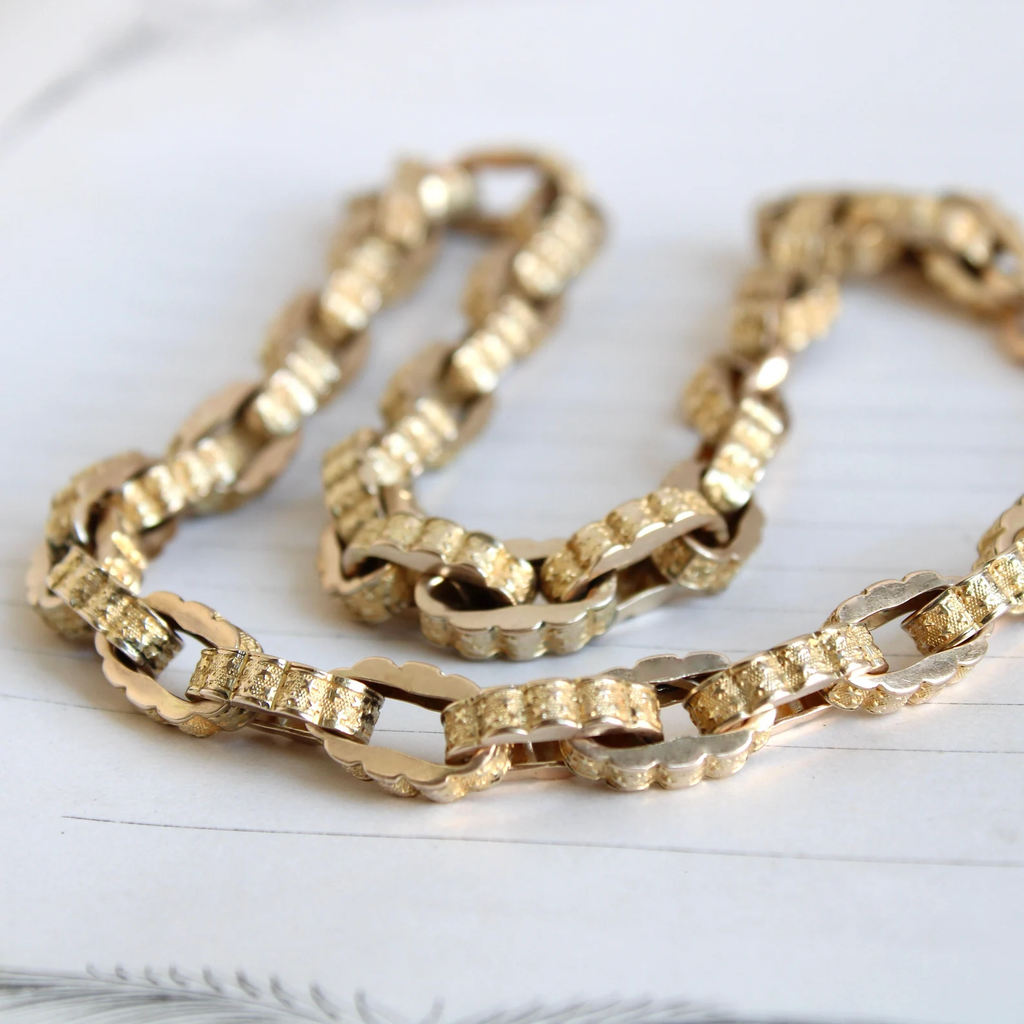 antique yellow gold chain with wide links embossed in a star pattern around the edges