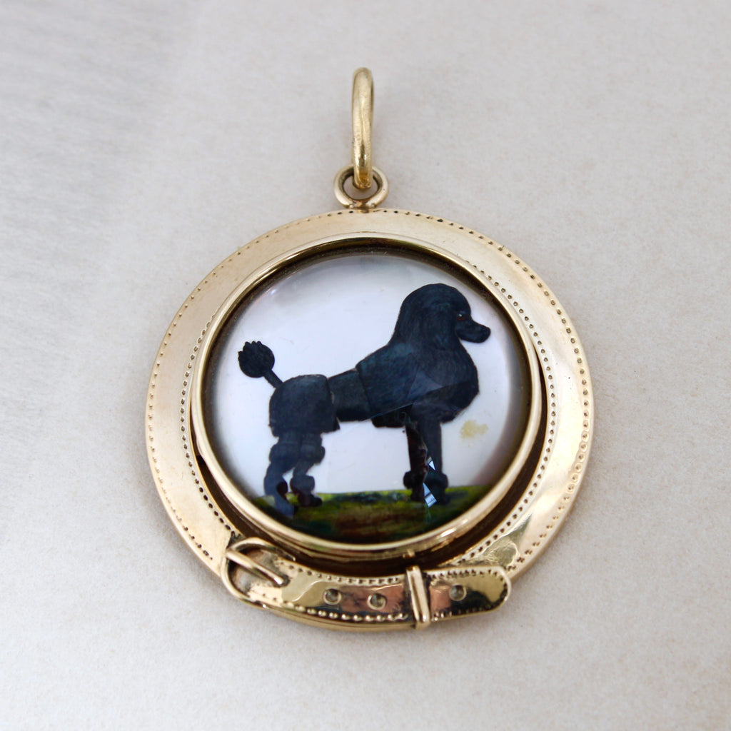 Antique yellow gold pendant with a black poodle portrait in the center with a belt buckle shaped bezel.