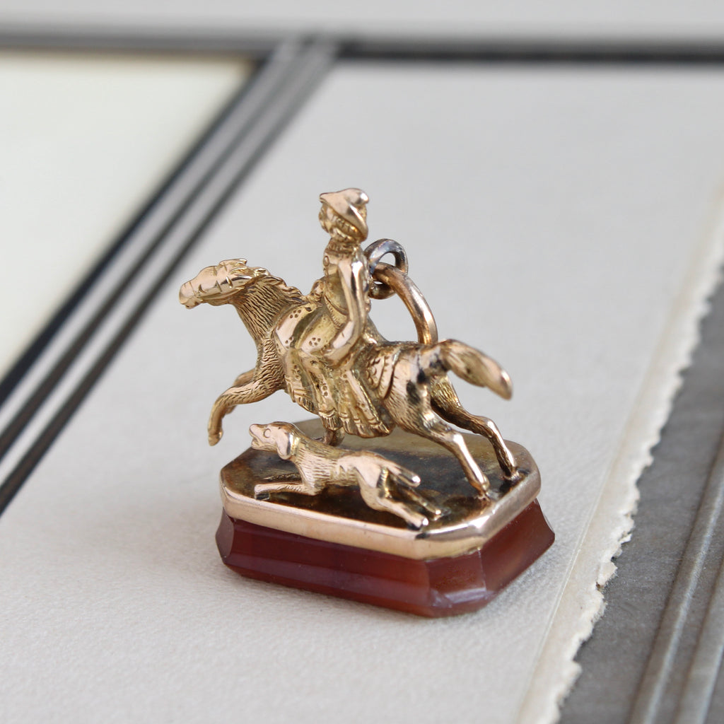 Antique yellow gold woman horse rider and running dog wax seal fob with a carved carnelian base.
