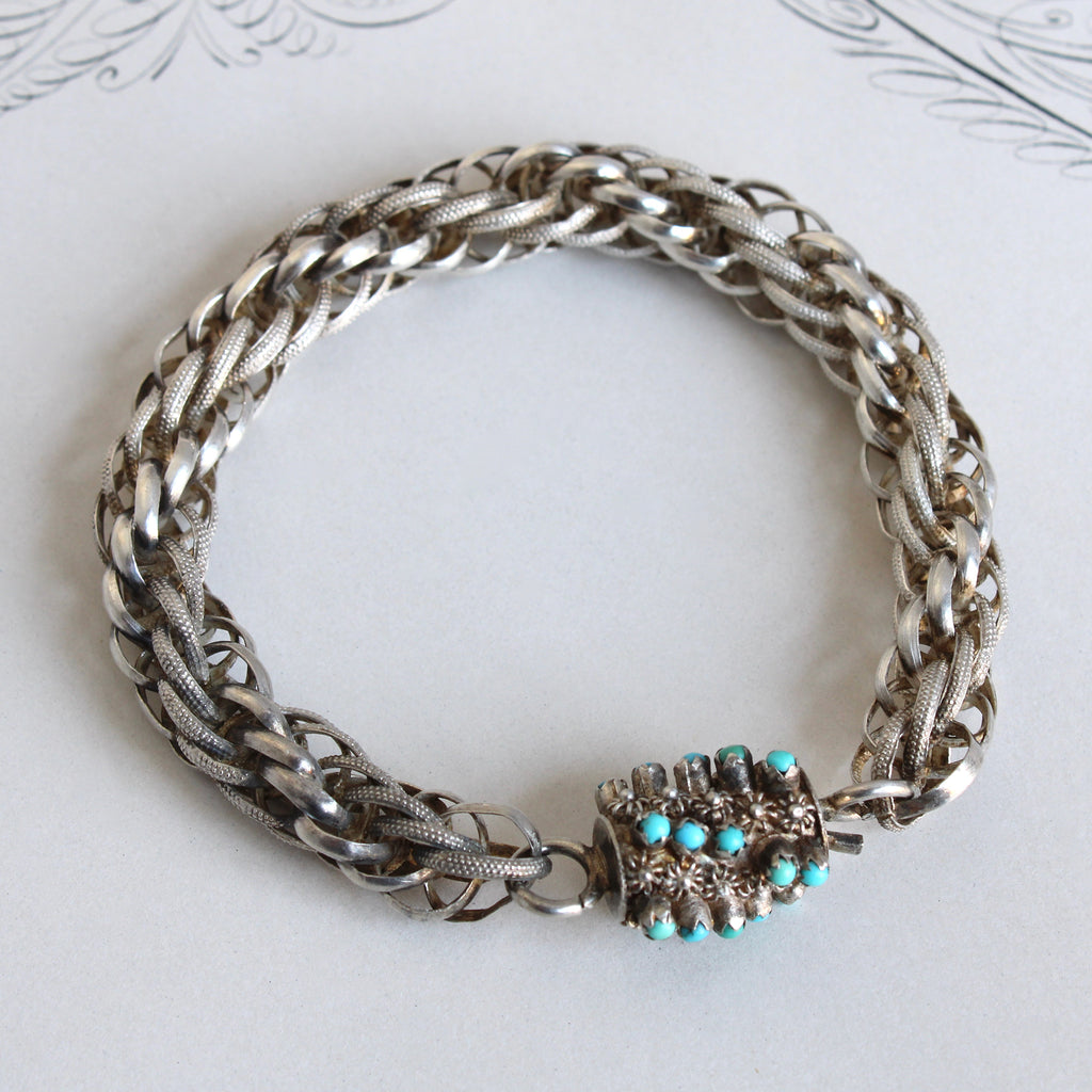 Antique sterling silver with a cannetille clasp set with tiny natural turquoise cabochons.