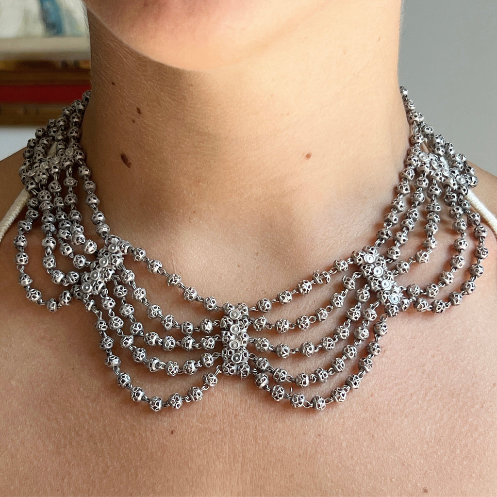 antique silver collar necklace with five rows of filigree beads swagged between silver filigree spacers.