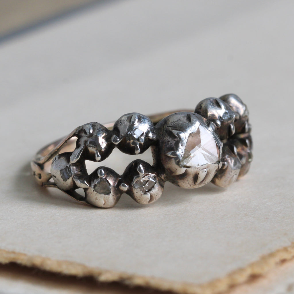 antique rose cut diamond ring with two rows of smaller diamonds in silver settings and one larger diamond in the center