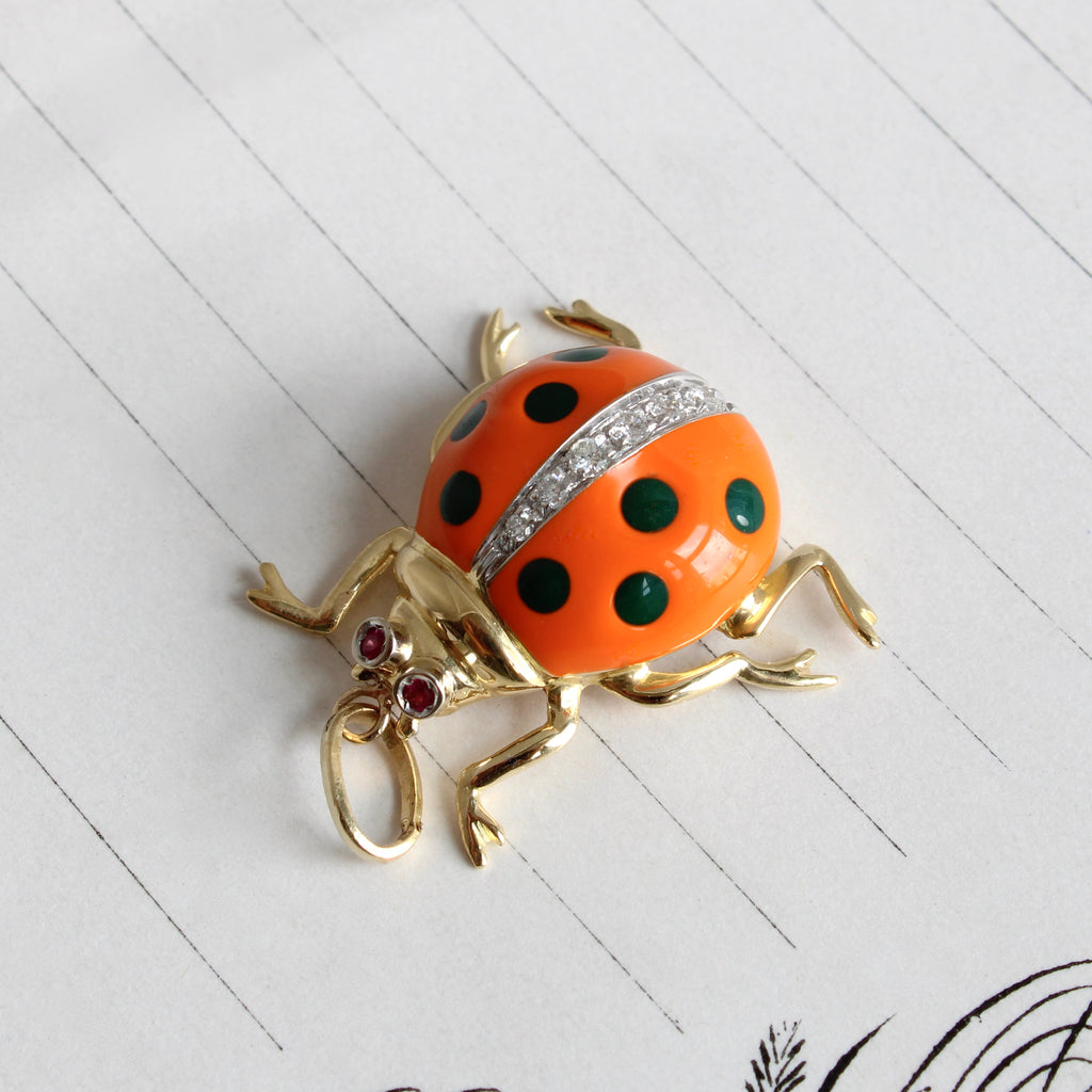 gold ladybug charm with orange enameled wings with black polka dots and diamonds down the back