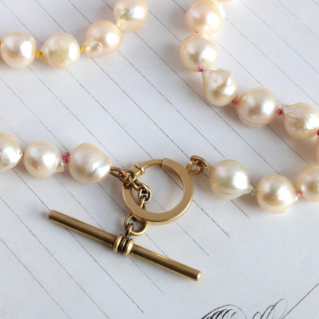 baroque freshwater pearls of creamy white with a yellow gold toggle clasp knotted on rainbow silk