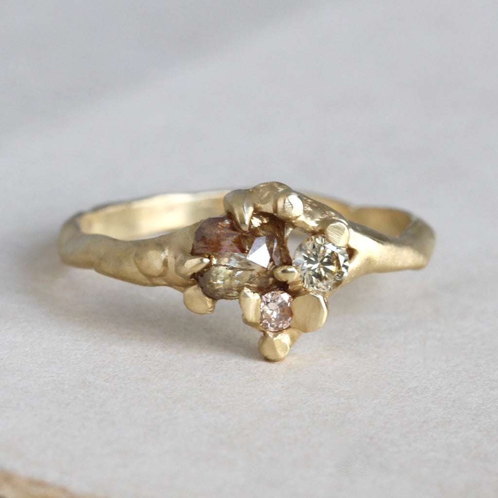 Handmade yellow gold ring with a rose cut amber diamond and two sparkling diamonds in a hammered texture setting and band