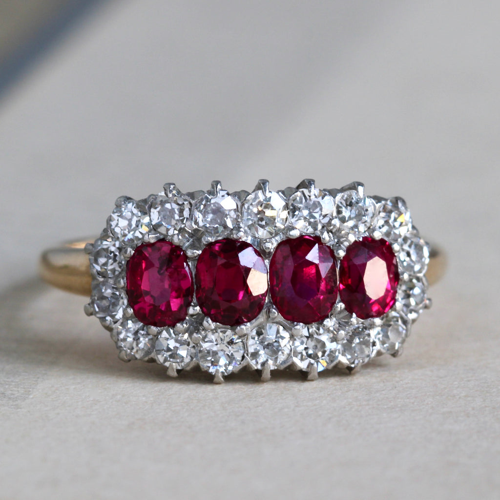 Antique two tone yellow gold and platinum ring with four faceted oval rubies in a halo of sparking diamonds.