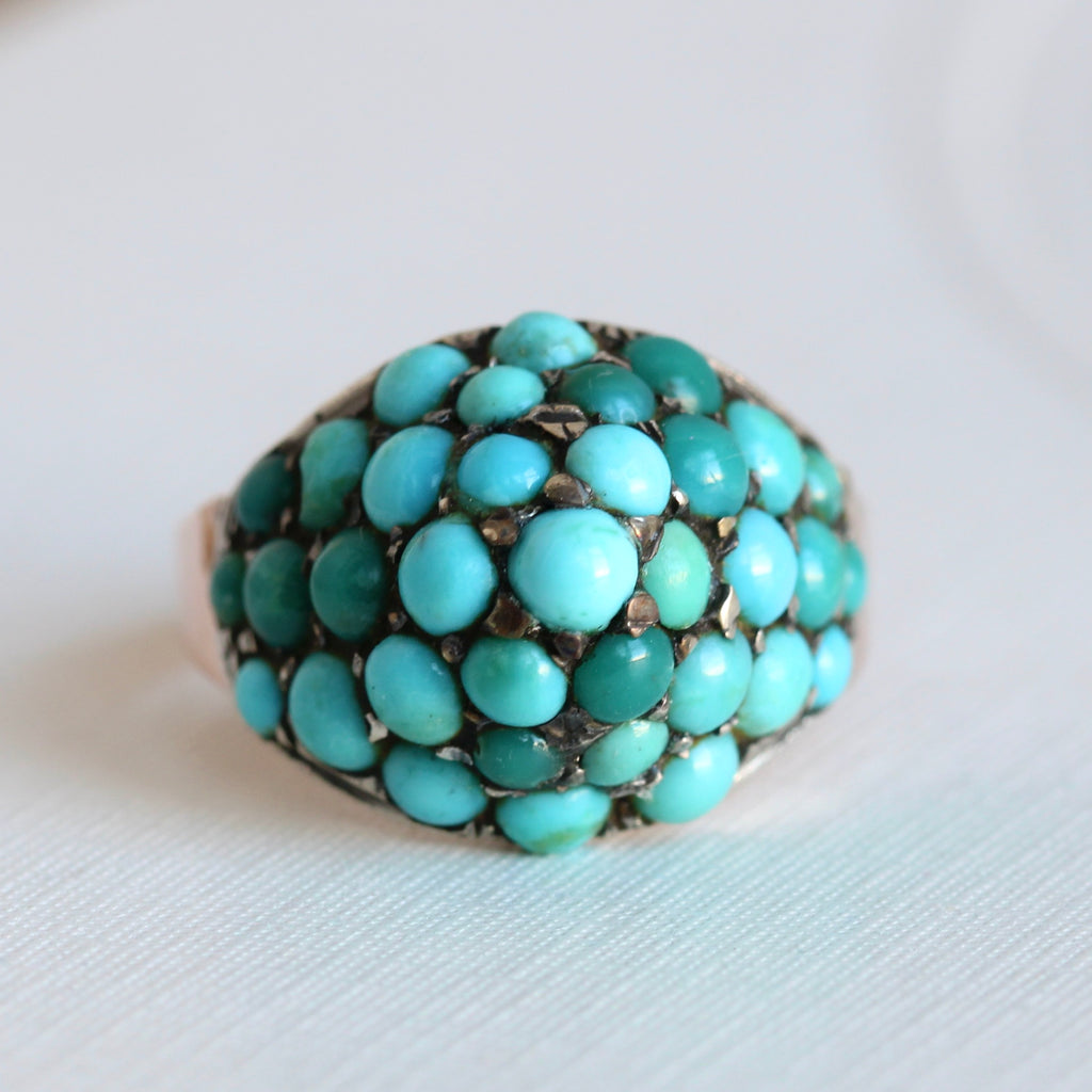antique dome ring closely set with turquoise cabochons in silver and a rose gold shank