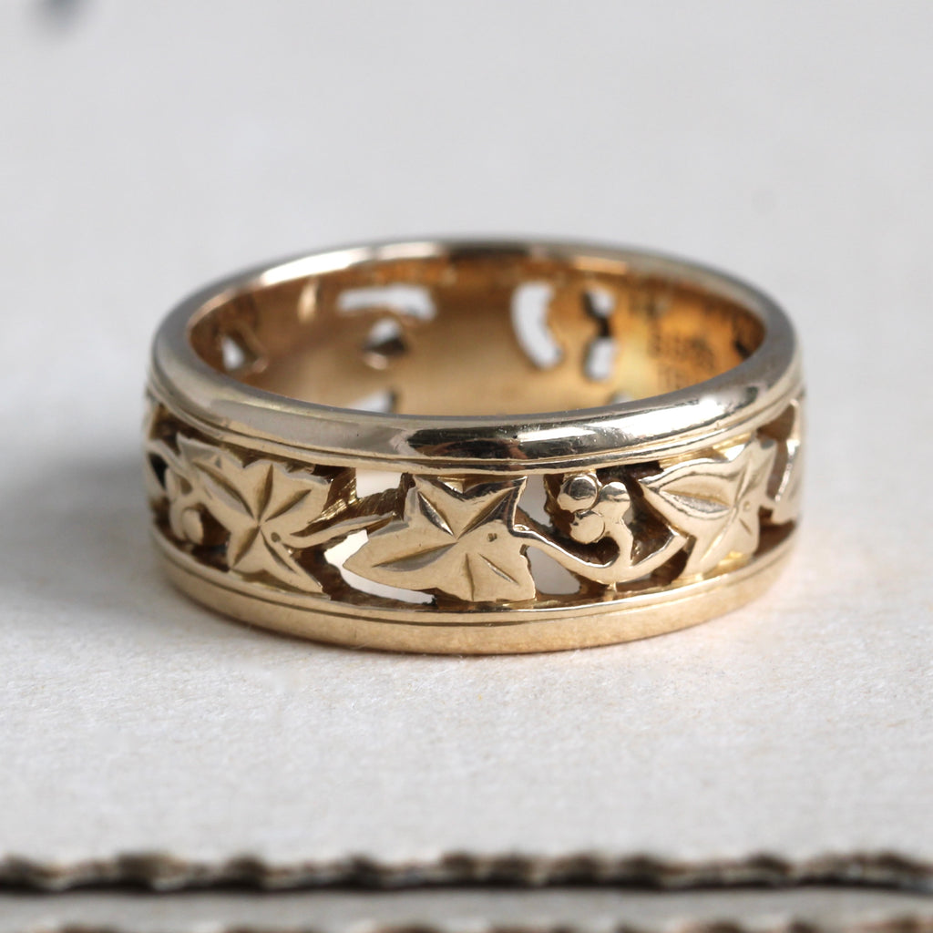 yellow gold band with cut out leaf and vine designs.