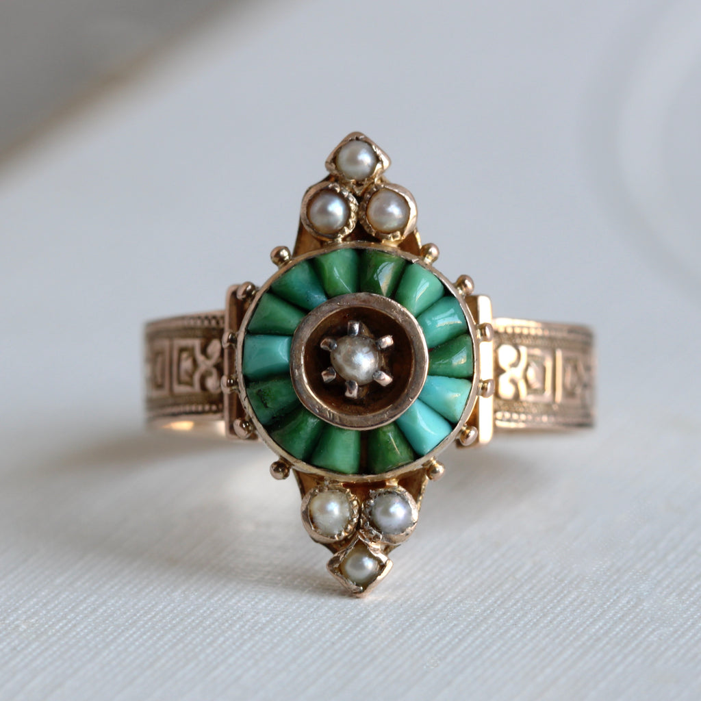 gold ring with a circle of triangular turquoise around a prong set pearl, and pearl accents north and south.