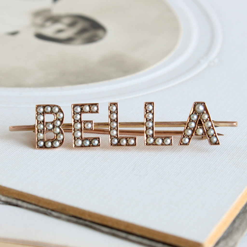 name brooch for bella in gold set with seed pearls on the letters