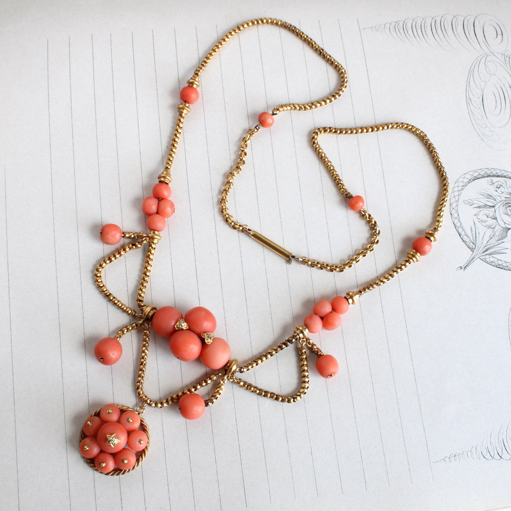 high karat gold necklace in a festoon style with swags of chain and coral balls decorating the chain and as a pendant