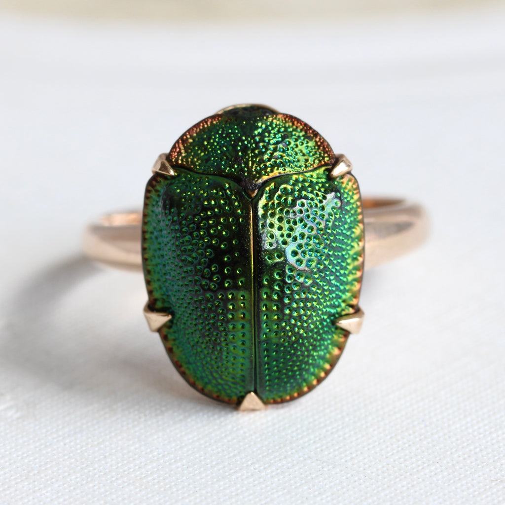 genuine  iridescent green beetle prong set as the main focal point of a 14k yellow gold ring