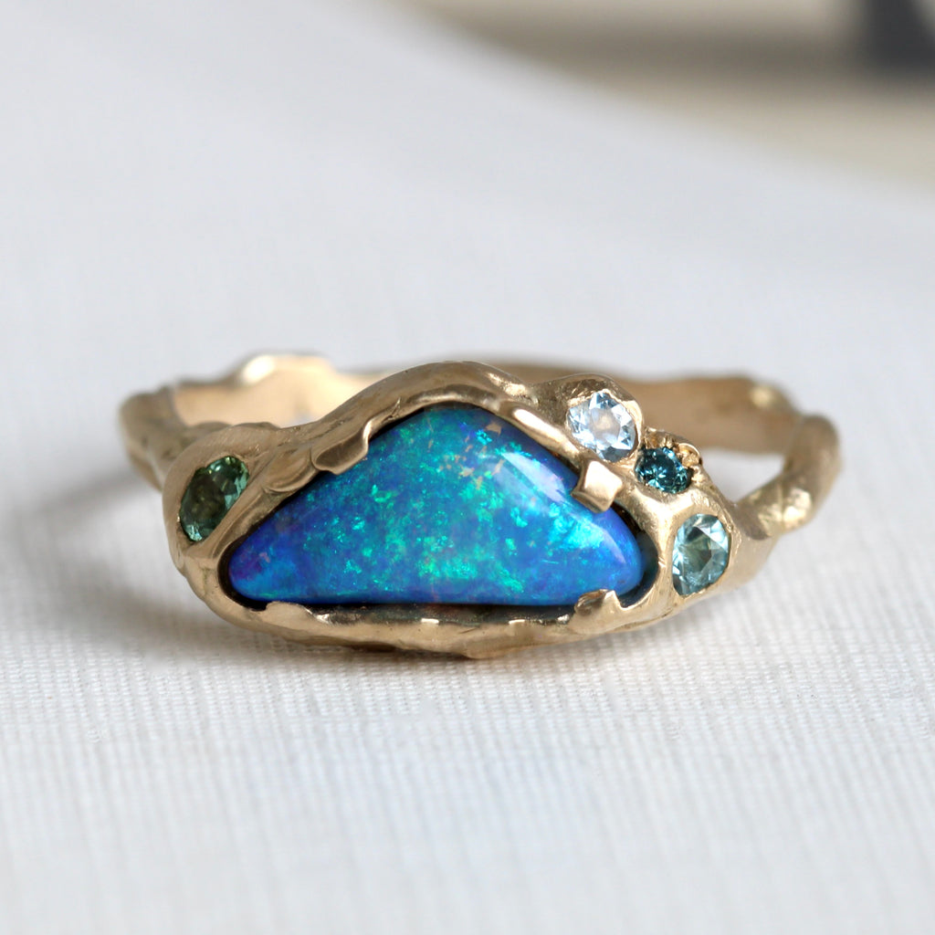 gold branch style ring with a cloud shaped blue boulder opal and blue gemstone accents