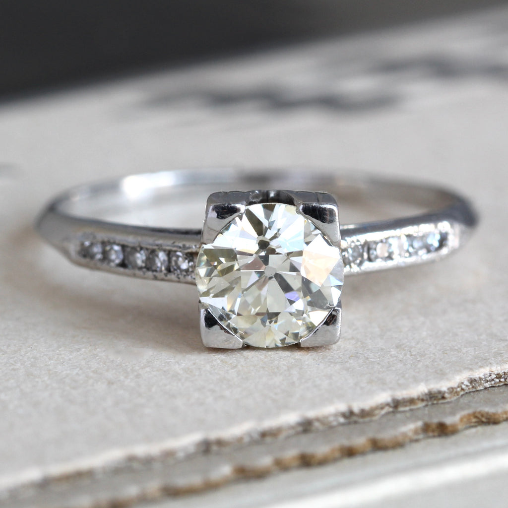 sleek platinum ring set with a large diamond in a box head with little diamond accents on each shoulder 