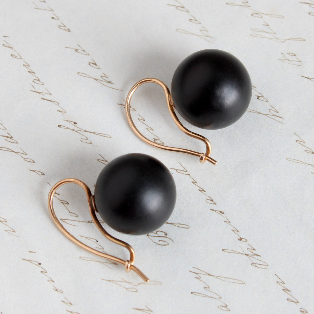 smooth black balls with a matte finish carved out of jet with gold ear wries