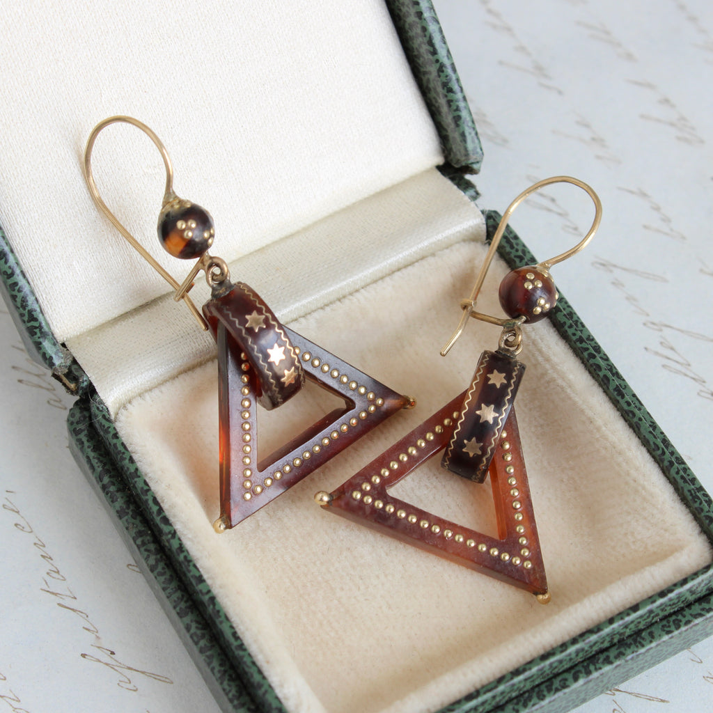 brown shell earrings designed as triangles fhanging from loops decorated with gold stars and dots