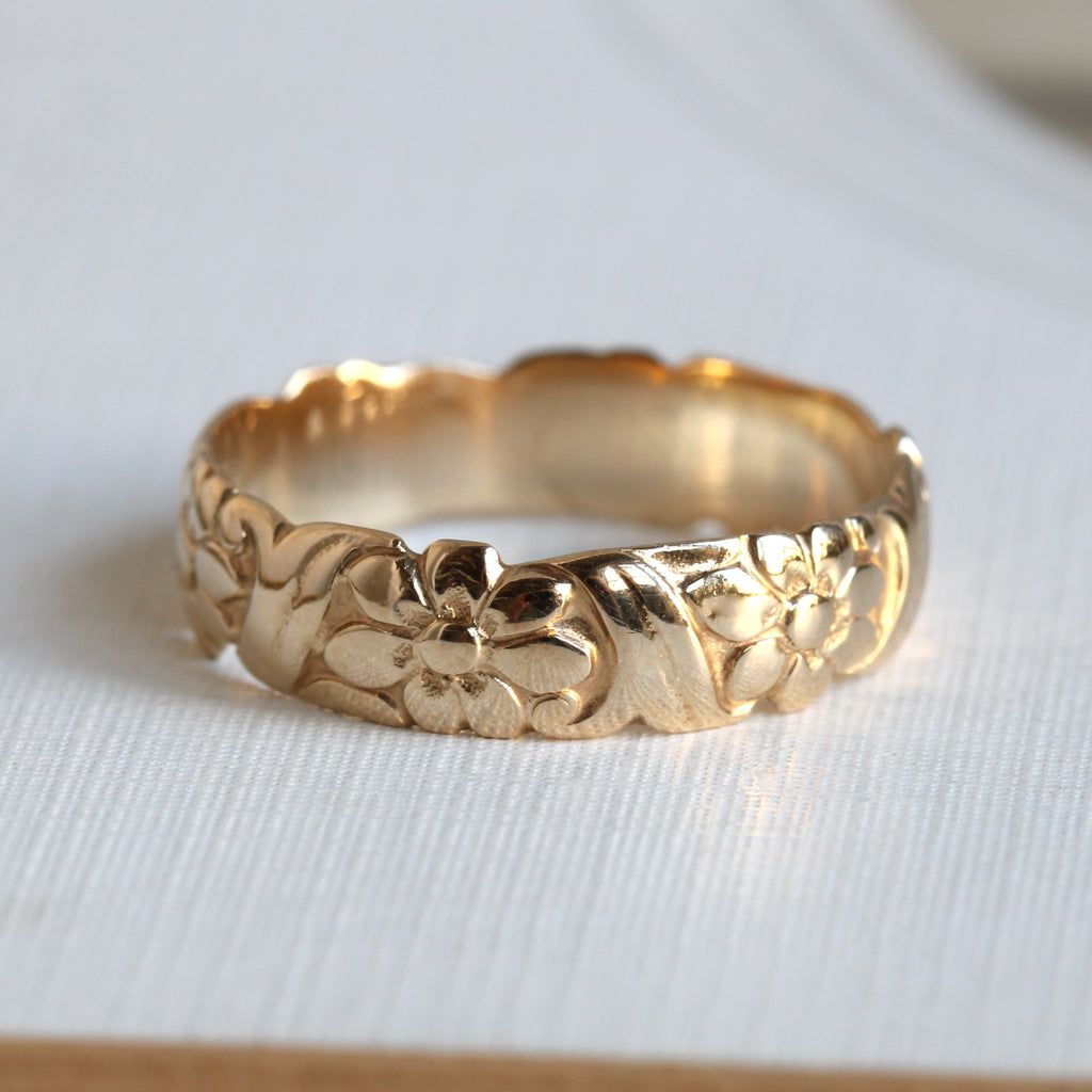 yellow gold band with a pattern of daises and scrolls chased around the outside of the band