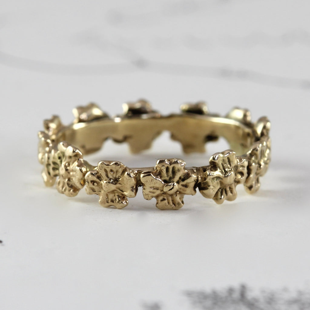 yellow gold ring with dogwood flowers carved all around the band.