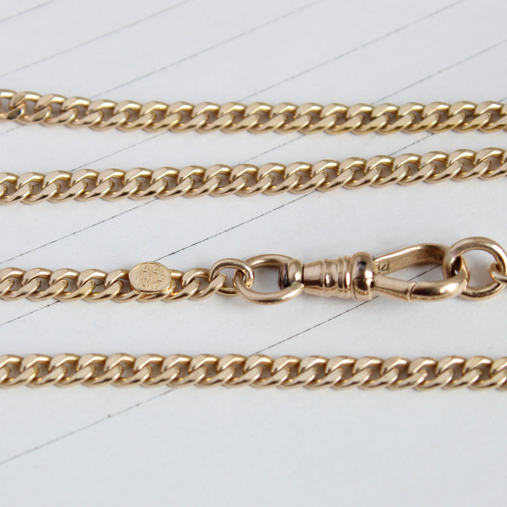 yellow gold curb chain with a gold clip clasp that doubles as a charm holder