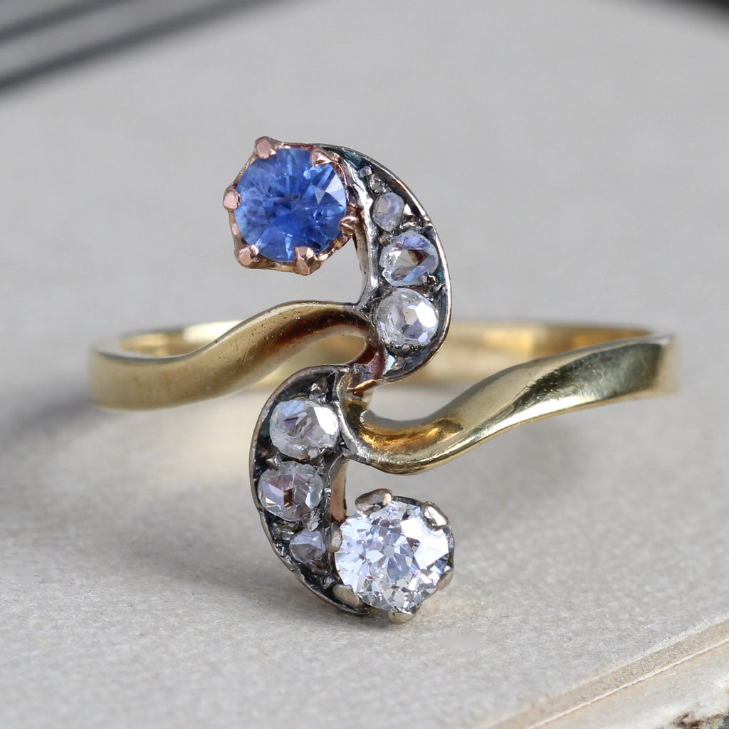 Antique yellow gold ring with sapphires and diamonds in an S shape.